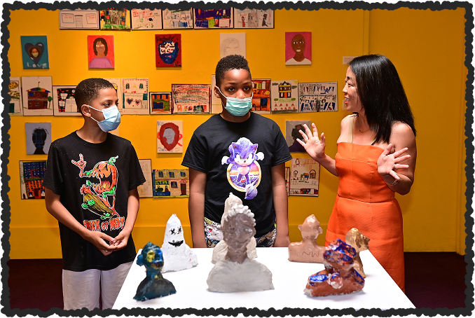 Photo of students standing in front of their artworks at Woodmere Art Museum.