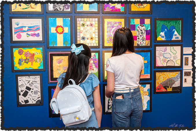 Photo of students looking at a wall of artwork.