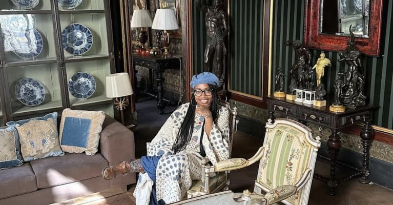 Photo of Jeannine A. Cook sitting in a room decorated with antiques.